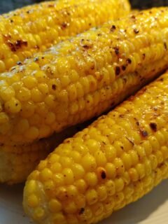 Close-up of perfectly cooked air fryer corn on the cob, glistening and seasoned.