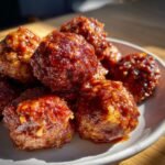 Close-up of a pile of Delicious BBQ Meatballs, glistening with a rich, savory sauce.