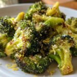 Close-up of Delicious Roasted Broccoli With Lemon Parmesan on a white plate, showing crispy florets and zest.
