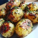 Close-up of a pile of Delicious Roasted Garlic Potatoes With Herbs, golden brown and sprinkled with fresh parsley.