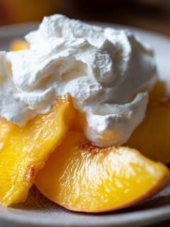 Close-up of sliced peaches topped with whipped cream, a delightful peaches and cream summer treat.
