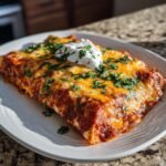 A close-up of Flavorful BBQ Chicken Enchiladas, topped with melted cheese, sour cream, and fresh cilantro.
