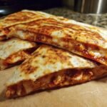 Close-up of a Flavorful BBQ Chicken Quesadilla, cut into wedges, showing melted cheese and BBQ chicken filling.