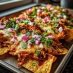 Close-up of Flavorful BBQ Pulled Chicken Nachos Cheesy Delight, topped with melted cheese, red onions, and cilantro.