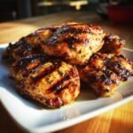 Close-up of juicy grilled chicken pieces with grill marks, seasoned with herbs, from a flavorful chicken marinade recipe.