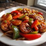 A close-up of a white plate filled with Flavorful Honey Garlic Shrimp Stir Fry, featuring plump shrimp and colorful bell peppers in a glossy sauce.