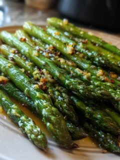 Close-up of tender, bright green Flavorful Roasted Asparagus With Lemon Garlic Butter served on a plate.