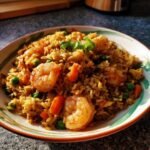 A close-up of flavorful shrimp fried rice, simple and tasty, with plump shrimp, peas, carrots, and green onions.