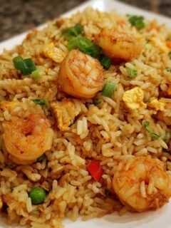 A close-up of flavorful shrimp fried rice, featuring plump shrimp, scrambled eggs, peas, and green onions.