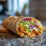 A delicious and spicy buffalo chicken wrap filled with shredded chicken, lettuce, red onion, and creamy sauce.