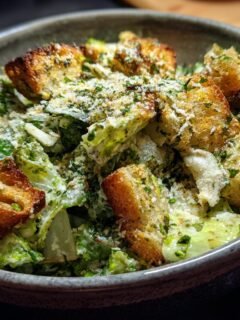 Close-up of an Irresistible Caesar Salad Recipe with crisp romaine lettuce, creamy dressing, golden croutons, and grated Parmesan cheese.