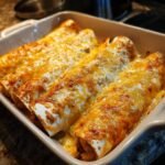 Close-up of Irresistible Chicken Enchiladas baked in a casserole dish, topped with melted golden cheese.