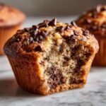 Close-up of an Irresistible Chocolate Chocolate Chip Muffin with a bite taken out, showing rich chocolate chips.