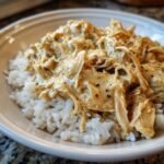 A bowl of fluffy white rice topped with creamy, shredded Irresistible Crockpot Crack Chicken.
