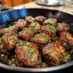 Close-up of Irresistible Garlic Butter Steak Bites sizzling in a cast iron skillet, garnished with fresh parsley.