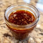 Close-up of a glass jar filled with Irresistible Honey BBQ Sauce, showing its rich, dark color and textured surface.