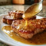 Close-up of juicy pork chops being drizzled with honey butter garlic sauce from a spoon.