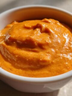 Close-up of a white bowl filled with creamy, orange Irresistible In And Out Sauce Recipe.