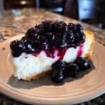 A decadent slice of Irresistible No Bake Blueberry Cheesecake, topped with fresh blueberries and syrup.