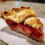 A close-up of a slice of Irresistible Strawberry Rhubarb Pie, showcasing the flaky crust and juicy fruit filling.