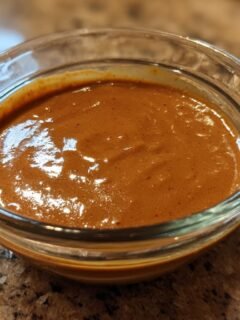 Close-up of Irresistible Thai Peanut Sauce recipe in a clear glass bowl, showcasing its smooth, rich texture.
