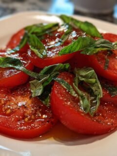 Close-up of sliced tomatoes marinated with herbs and dressing, a refreshing Memorial Day delight.