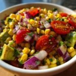 Close-up of Zesty Avocado Corn Salad with cherry tomatoes, avocado, corn, and red onion.