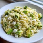A close-up serving of vibrant Avocado Feta Orzo Salad featuring orzo pasta, bright green avocado chunks, and white feta cheese.