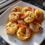 Close-up of plump, juicy Baked Shrimp Scampi coated in garlic butter and parsley on a white plate.