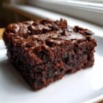 Close-up of a rich, fudgy slice of Zucchini Chocolate Brownies topped with melted chocolate chips.
