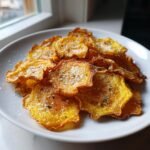 A pile of crispy, golden Garlic Parmesan Yellow Squash Chips dusted with grated cheese and herbs on a white plate.