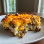 A close-up serving of Ground Beef Cauliflower Rice Casserole topped with melted cheddar cheese.