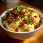 A close-up of Instant Pot Loaded Mashed Cauliflower topped with crispy bacon bits and fresh green onions.