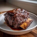 Close-up of a single, tender, glazed Instant Pot Short Ribs served in a shallow bowl.