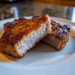 Close-up of two thick, juicy Fried Pork Chops cut in half showing a golden-brown crust and tender pink interior.