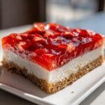 Close-up of a layered Strawberry Pretzel Dessert slice showing a pretzel crust, cream cheese filling, and strawberry gelatin topping.
