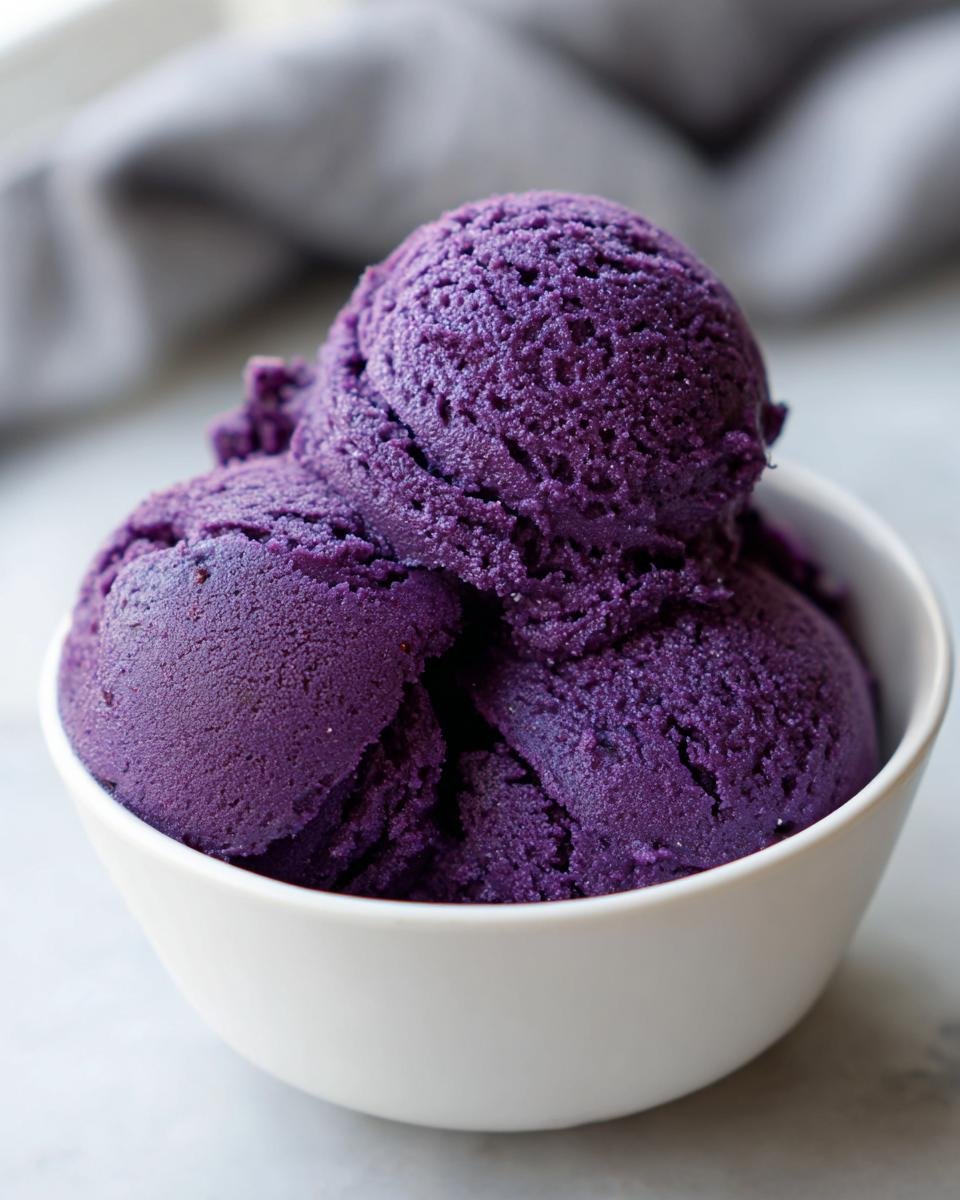 Three scoops of vibrant, deep purple Blueberry Nice Cream served in a small white bowl.