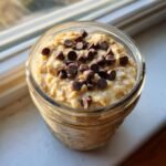 Overhead close-up of Chocolate Chip Banana Overnight Oats topped with mini chocolate chips in a glass jar.
