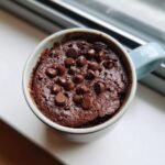 Overhead view of a freshly baked Chocolate Mug Cake topped generously with melted chocolate chips.