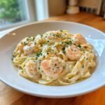 A white bowl filled with rich Creamy Shrimp Fettuccine, topped generously with pink shrimp and fresh parsley.