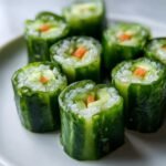 Close-up of several fresh Cucumber Sushi Rolls, featuring rice and carrot filling wrapped in cucumber skin.