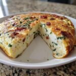 A thick, golden-brown Easy Bacon Spinach Frittata cut in half, showing fluffy interior with bacon and green spinach.