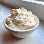 A small white bowl filled with fluffy, creamy white fruit dip, ready for serving.