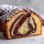 Close-up of a slice of German Marble Cake showing a distinct vanilla and chocolate swirl pattern, dusted with powdered sugar.
