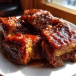 Close-up of tender Country Style Pork Ribs coated in a thick, glossy, dark red barbecue glaze.