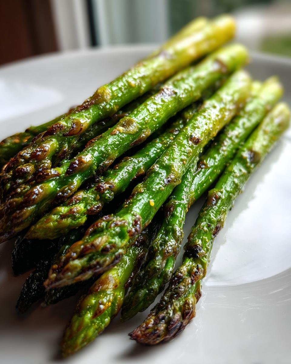 Close-up of bright green, slightly charred Grilled Asparagus spears resting on a white plate.