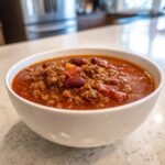 Close-up of a white bowl filled with rich, savory Taco Soup featuring ground beef, kidney beans, and tomatoes.