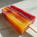 Close-up of a brightly colored, layered Bahama Mama Ice Pops with red, orange, and yellow stripes.