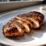 Close-up of juicy, sliced Lemongrass Grilled Chicken breast with visible grill marks on a white plate.