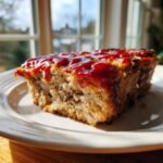 A close-up slice of moist Lipton Onion Soup Meatloaf topped with a thick, glossy ketchup glaze.